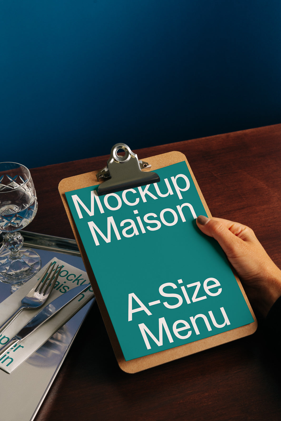 PSD mockup of a clipboard holding an A-size menu, with elegant tableware and a dark wooden surface, providing a sophisticated dining scene.