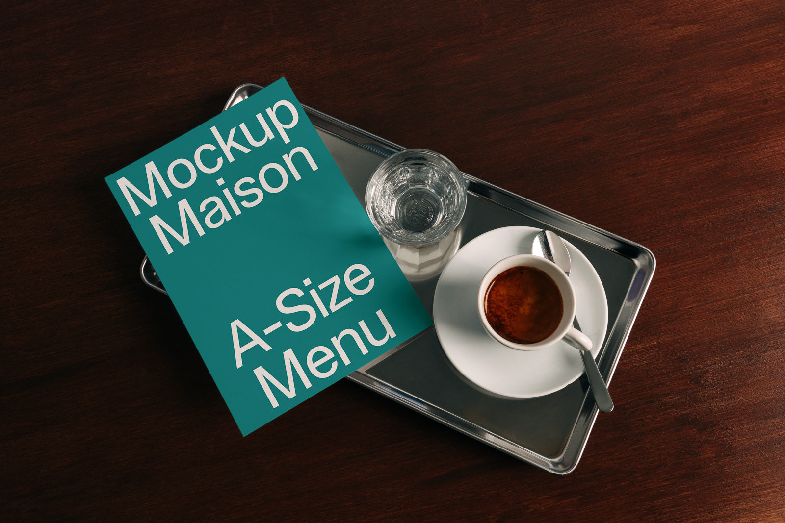 PSD mockup of an A-size menu placed on a metal tray with a cup of espresso and a glass of water on a wooden table.