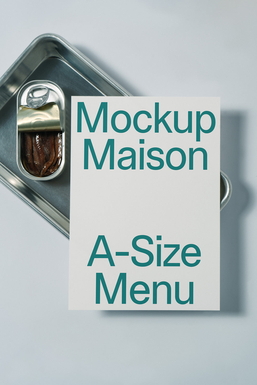 PSD mockup of a white A-size menu card placed on a metal tray with an opened can of sardines beside it.