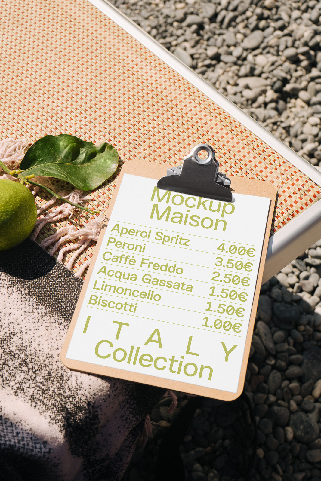 PSD mockup of a clipboard menu on a textile surface, featuring drinks and snacks like Aperol Spritz and Biscotti with prices in euros, next to a lime and leaves.
