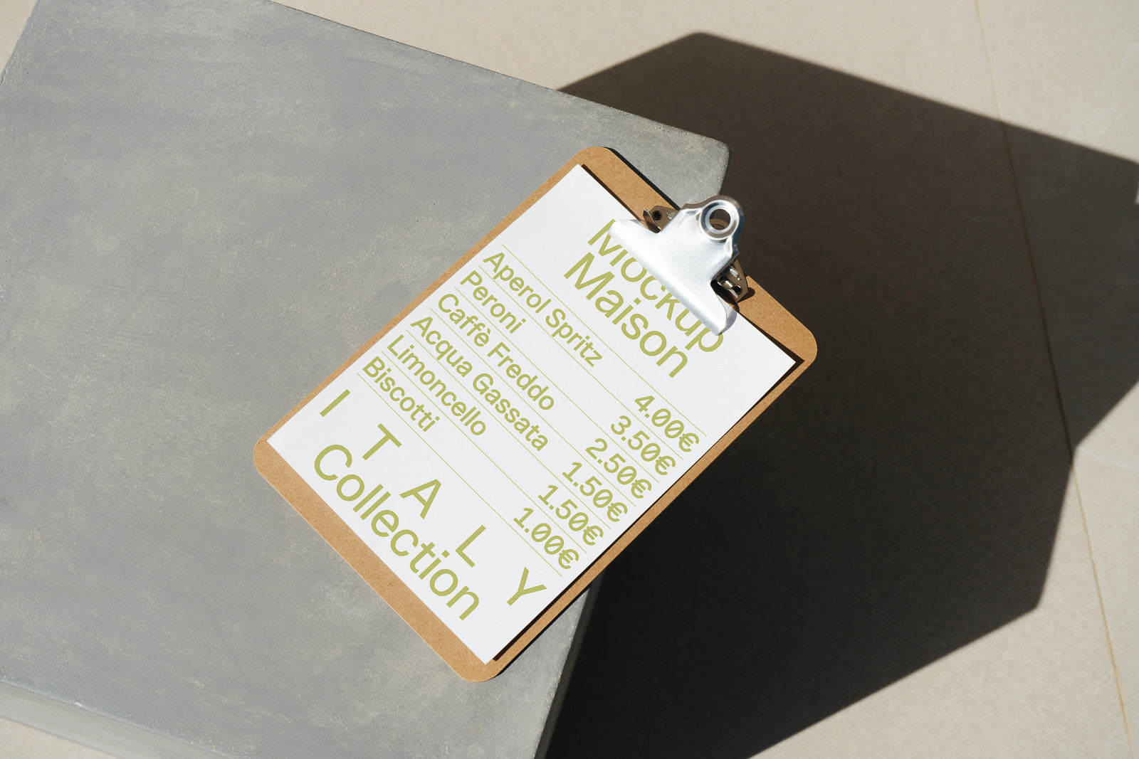 PSD mockup of a clipboard with a menu featuring Italian items, including Aperol Spritz and Caffè Freddo, priced in euros, placed on a concrete surface.