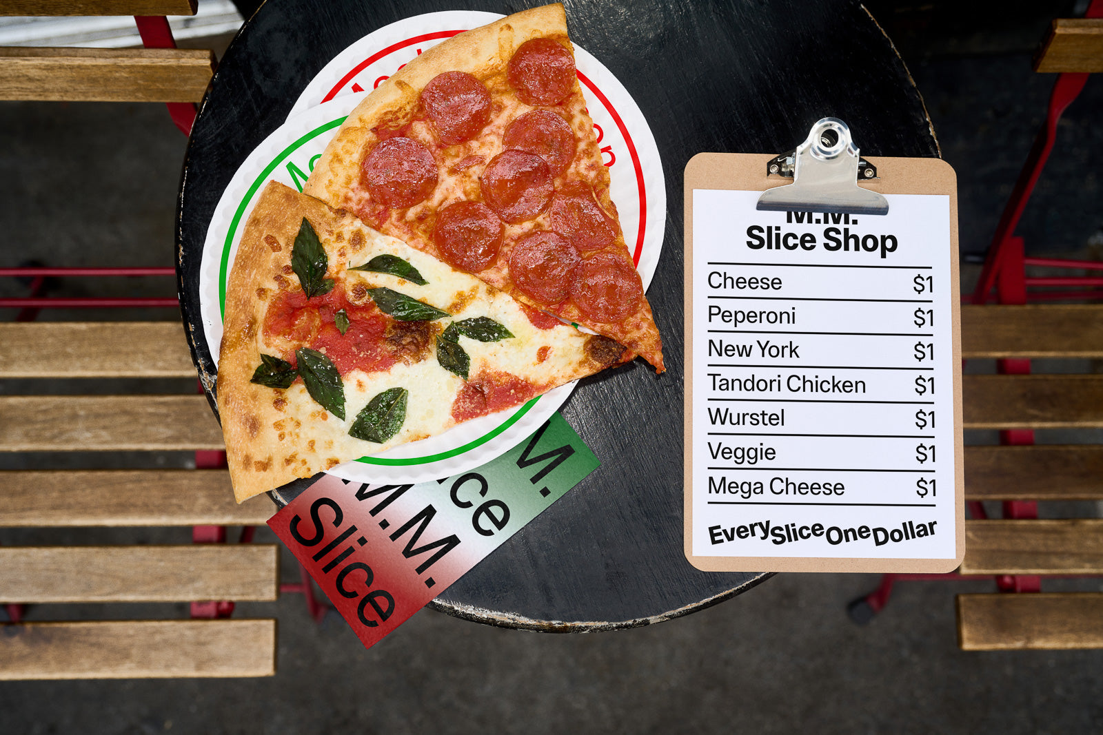 PSD mockup of a round table with two pizza slices, one with pepperoni and one with basil, next to a menu offering $1 pizza slices.