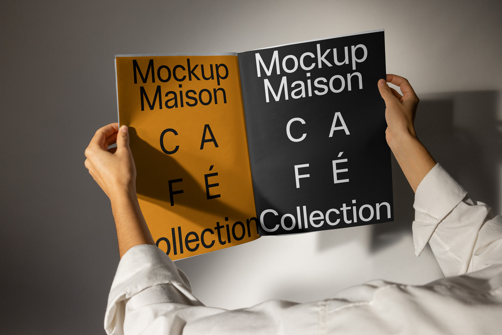 PSD mockup of hands holding a two-page spread, featuring "Mockup Maison" and "Café Collection" in bold black and white text on brown and dark backgrounds.