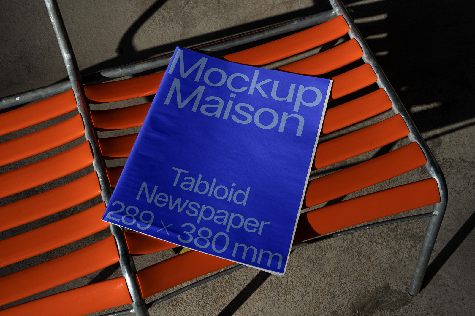 PSD mockup of a tabloid newspaper with blue cover displaying "Mockup Maison" on an orange chair, size 289 x 380 mm.