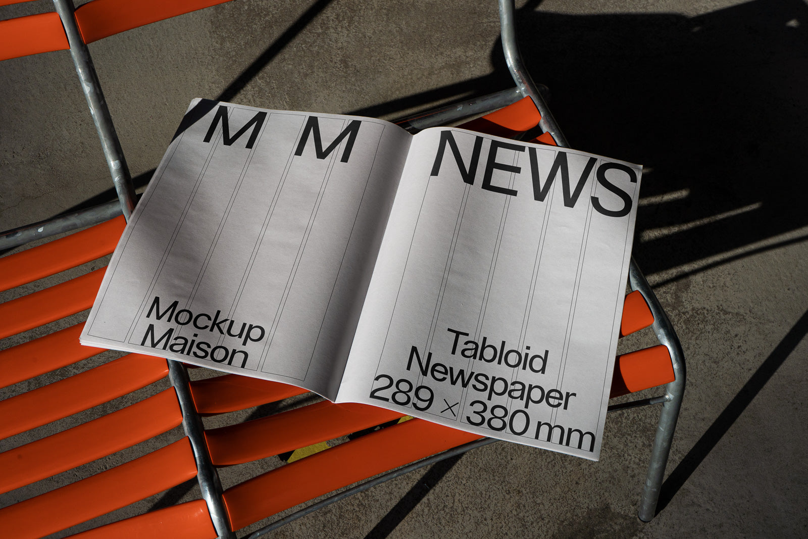 PSD mockup of an open tabloid newspaper with bold text, placed on an orange metal chair. Shadows create dynamic contrast in the image's composition.