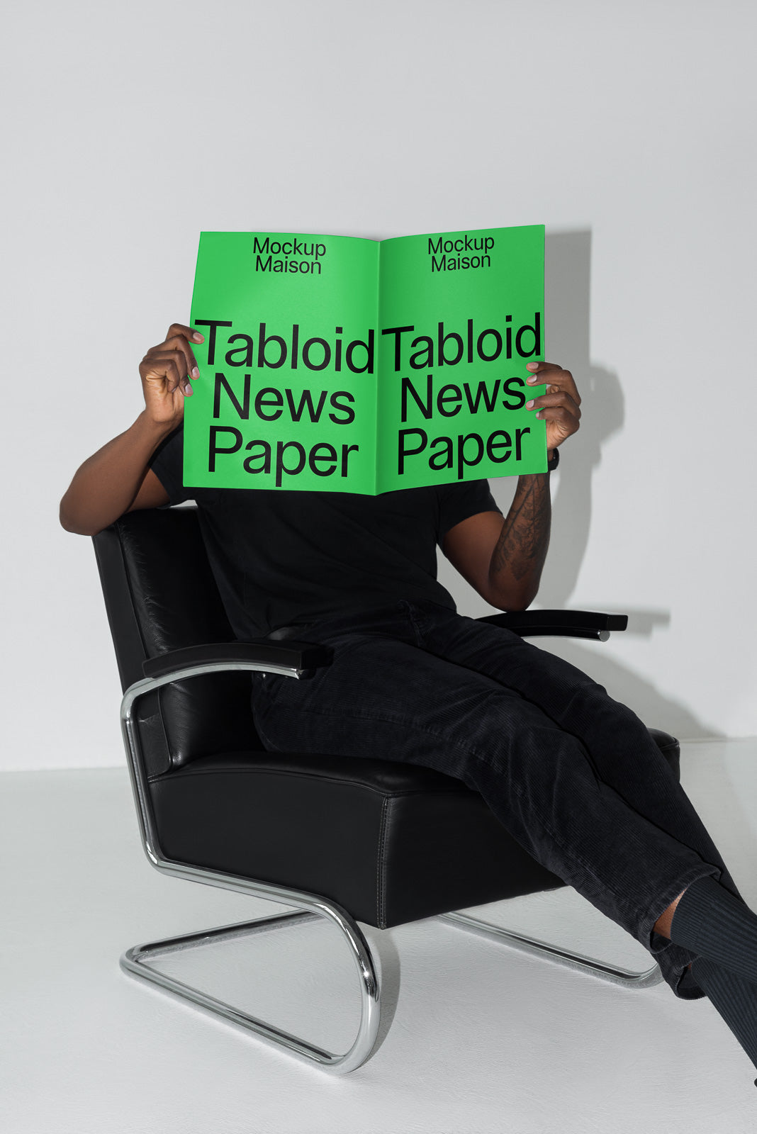 PSD mockup of a person sitting in a modern chair, holding a green tabloid newspaper with bold text "Tabloid News Paper" on the cover.