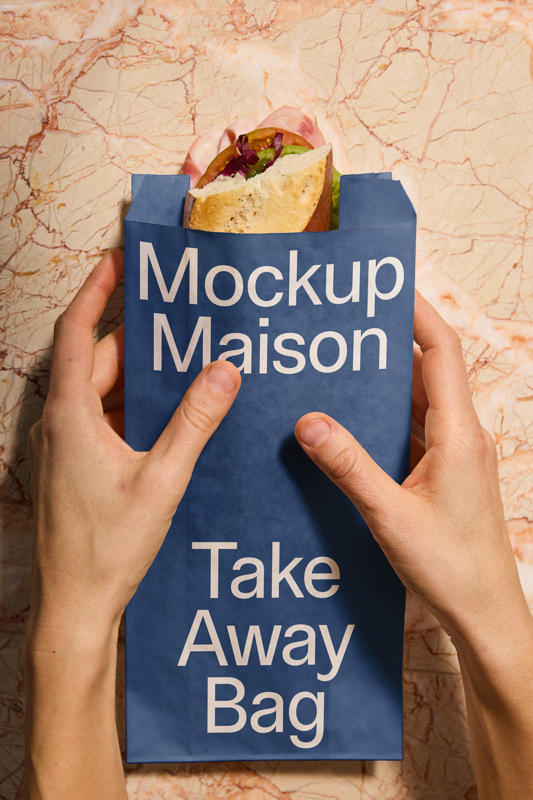 PSD mockup of hands holding a blue take-away bag with a sandwich inside against a marble background, labeled "Mockup Maison Take Away Bag."