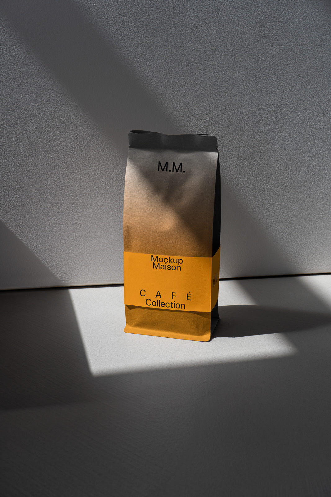PSD mockup of a coffee bag with "M.M." branding, featuring a gradient design and "Café Collection" label, standing on a textured surface in natural light.