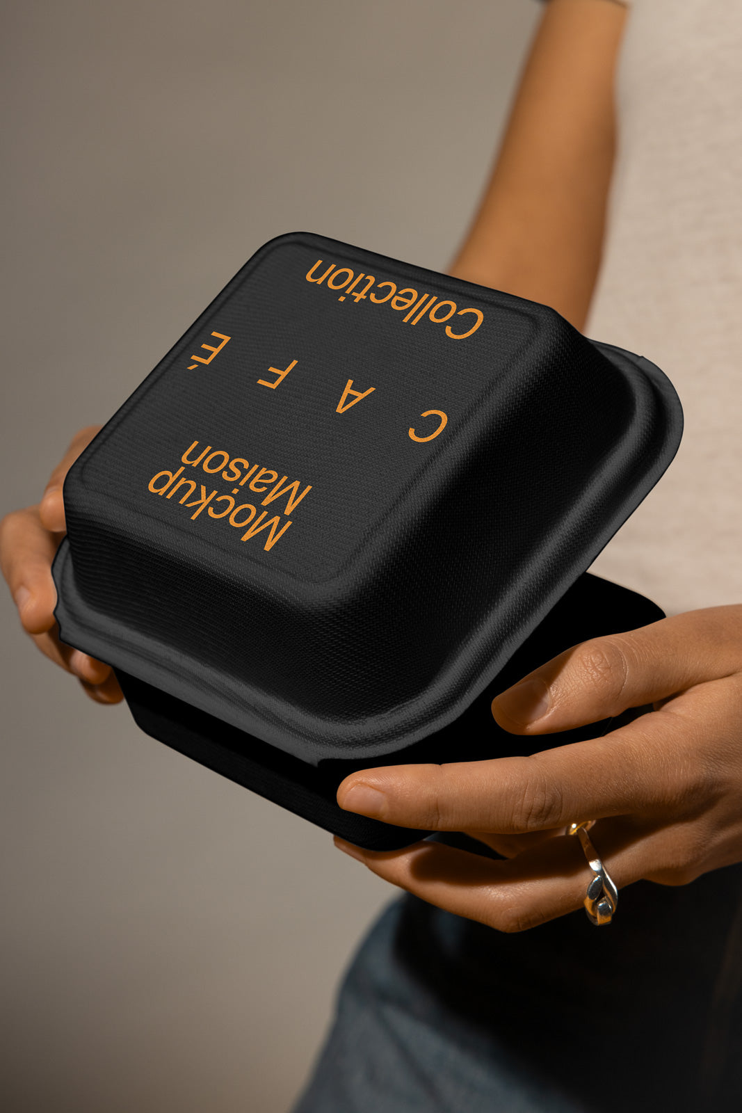 PSD mockup of hands holding an eco-friendly black food container featuring "Cafe Collection" text.