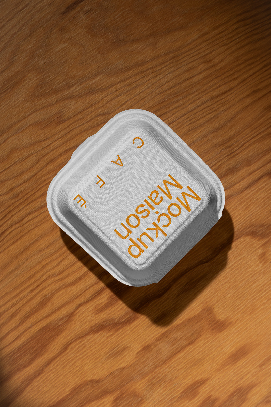 PSD mockup of a white food container with "Mockup Maison Cafe" text in orange on a wooden table background.
