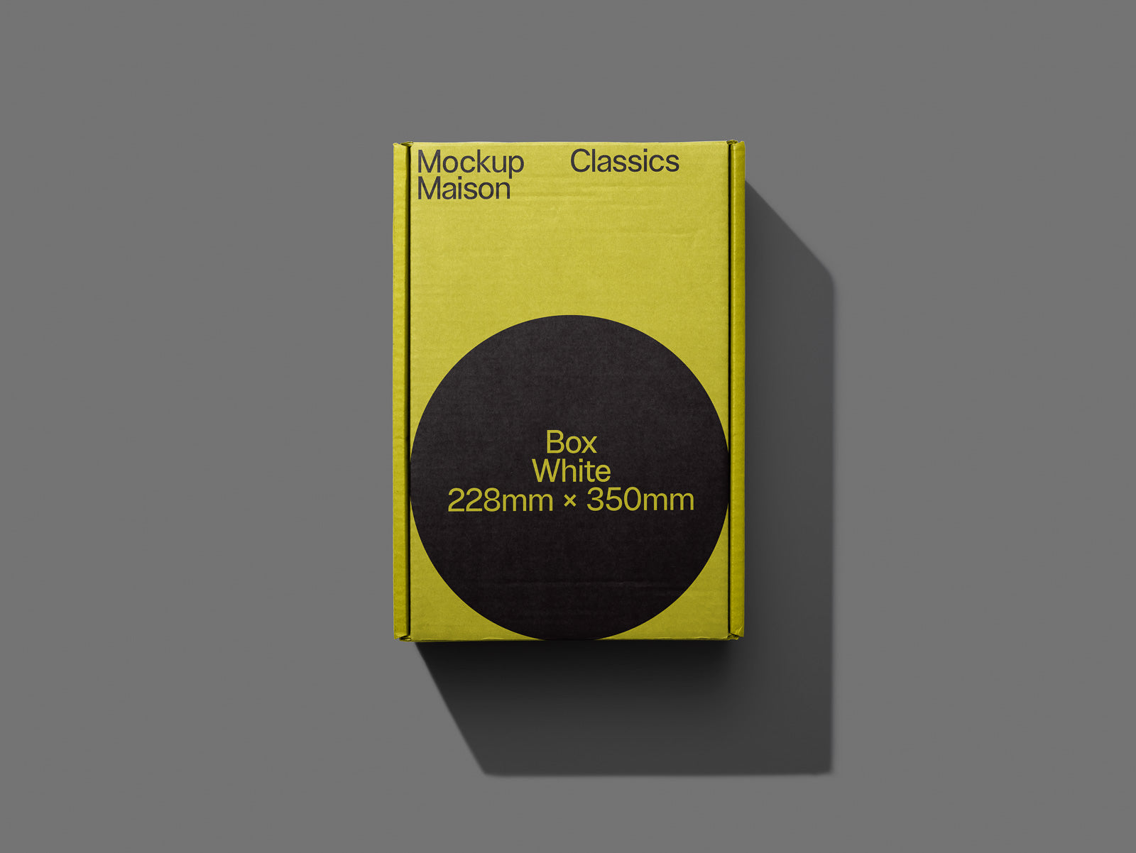 PSD mockup of a yellow cardboard box with black circular label displaying "Box White 228mm x 350mm" against a gray background.