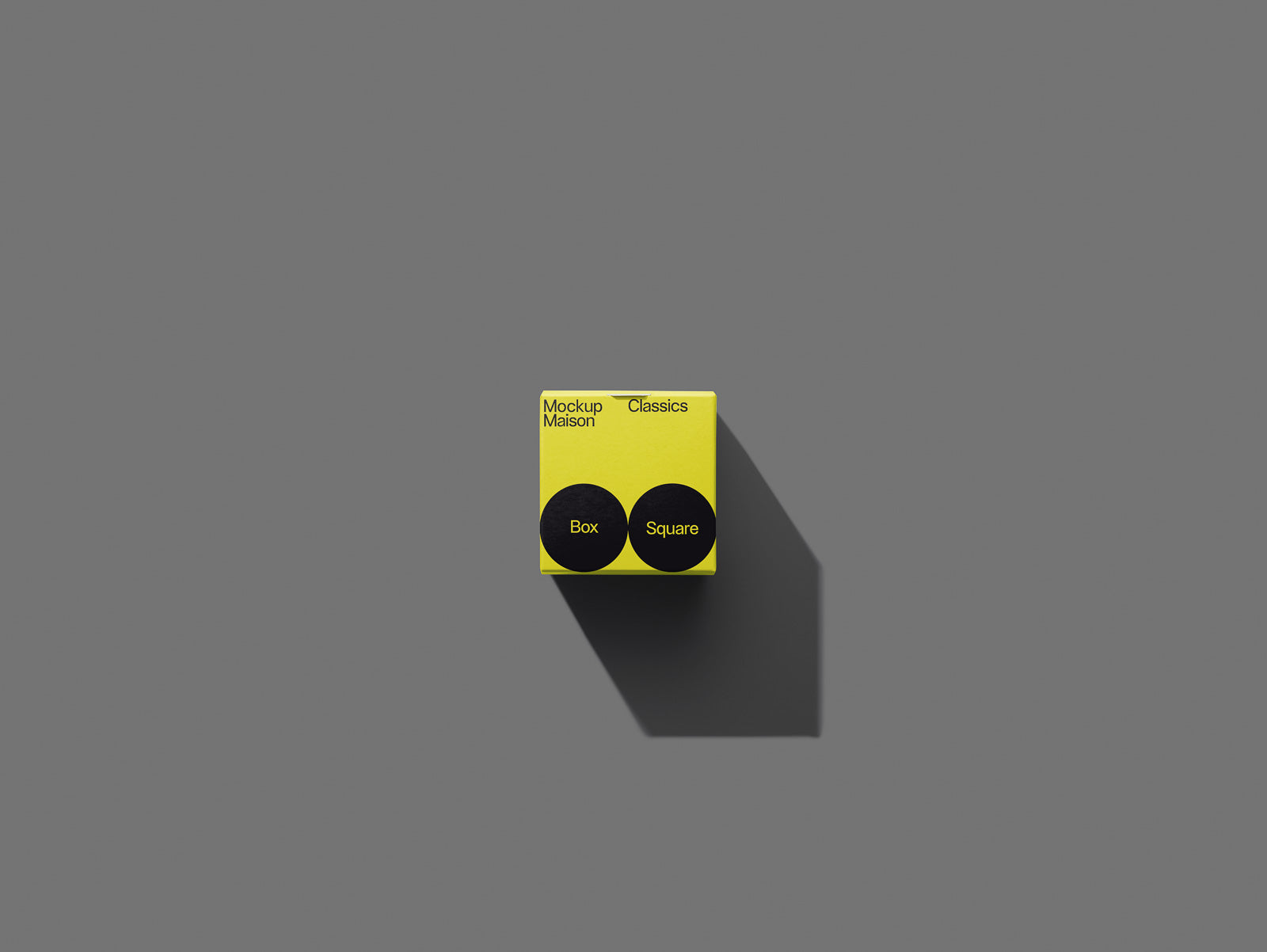 PSD mockup of a small yellow box with black circular elements, labeled "Mockup Maison Classics" in a minimalist design on a gray background.