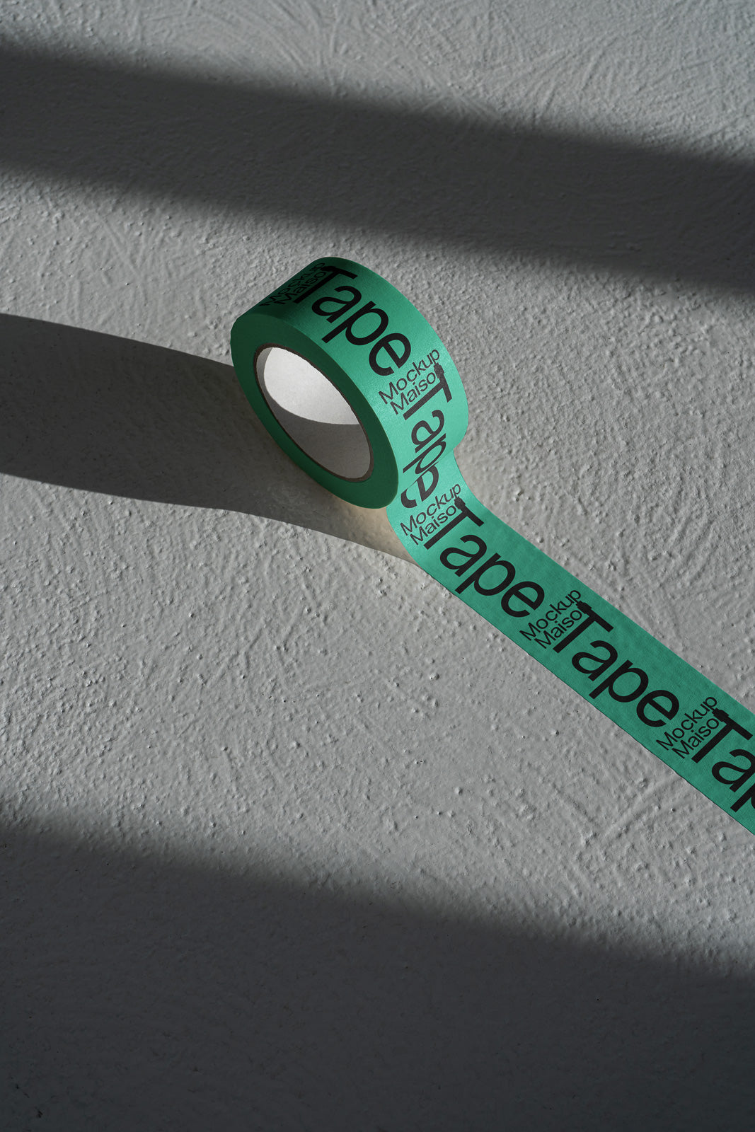 PSD mockup of a green roll of tape with text, casting shadows on a textured surface, providing a realistic presentation, enhancing visual appeal.