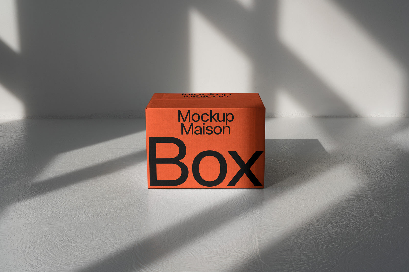 PSD mockup of an orange cardboard box labeled "Mockup Maison Box" with shadow patterns on a textured surface, suitable for branding visualization.