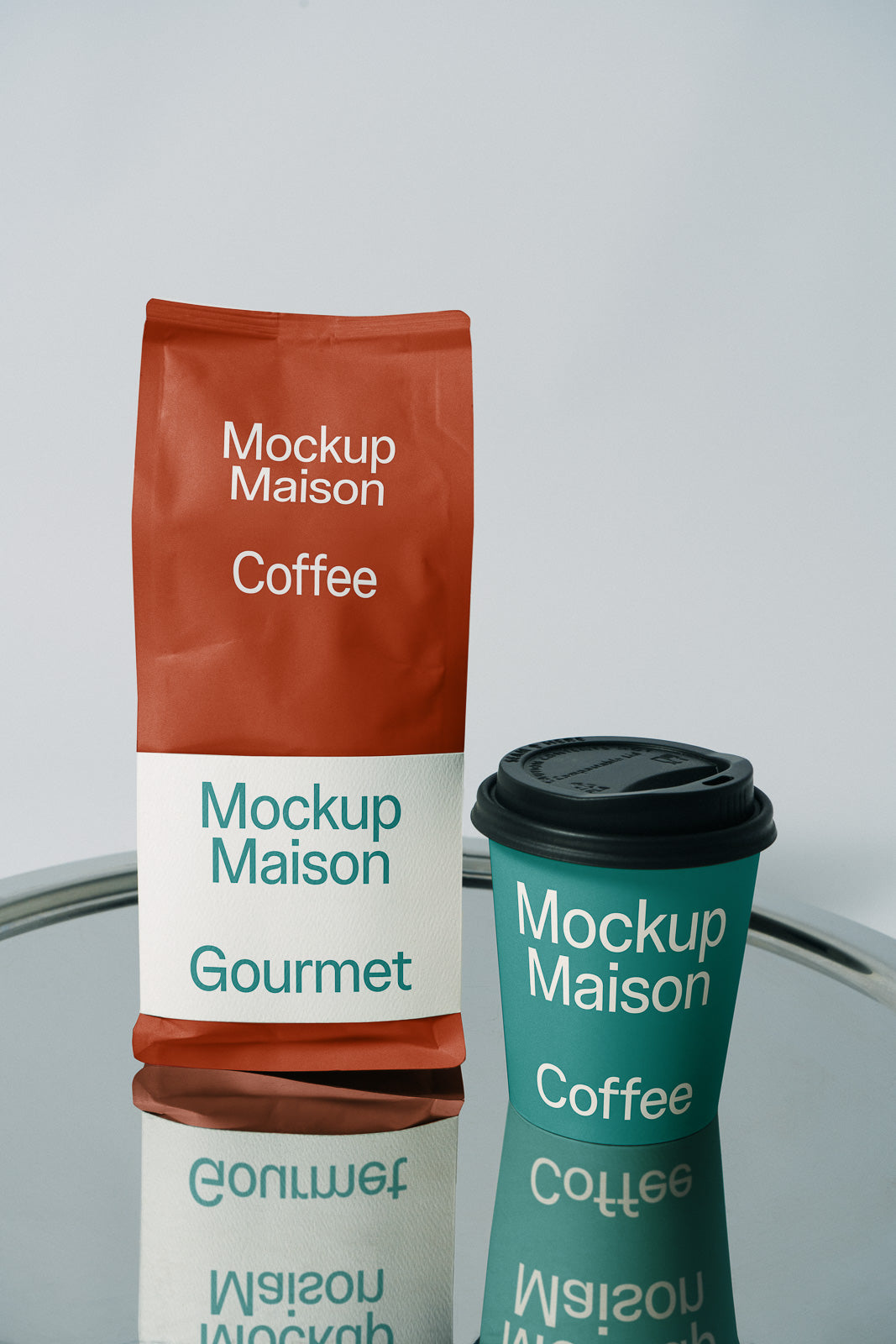 PSD mockup of a branded coffee package and takeaway cup labeled "Mockup Maison Gourmet" on a reflective surface.