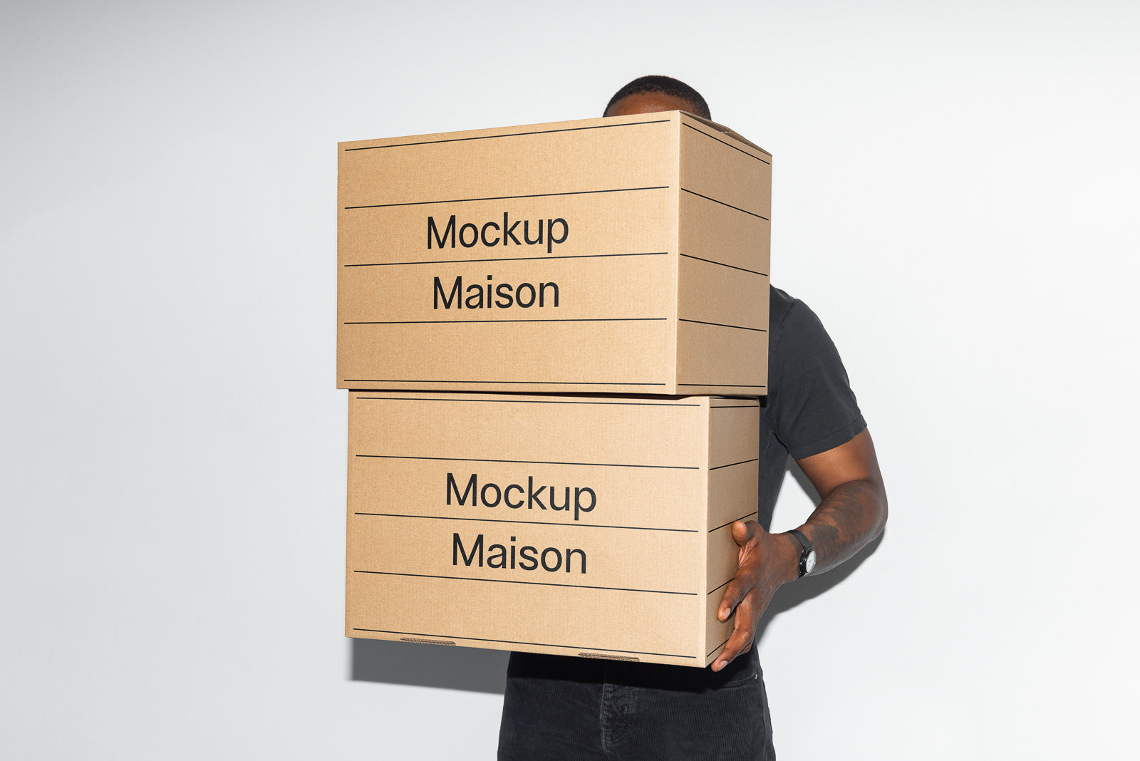 PSD mockup of two stacked cardboard boxes labeled "Mockup Maison," held by an unseen person, against a plain background.