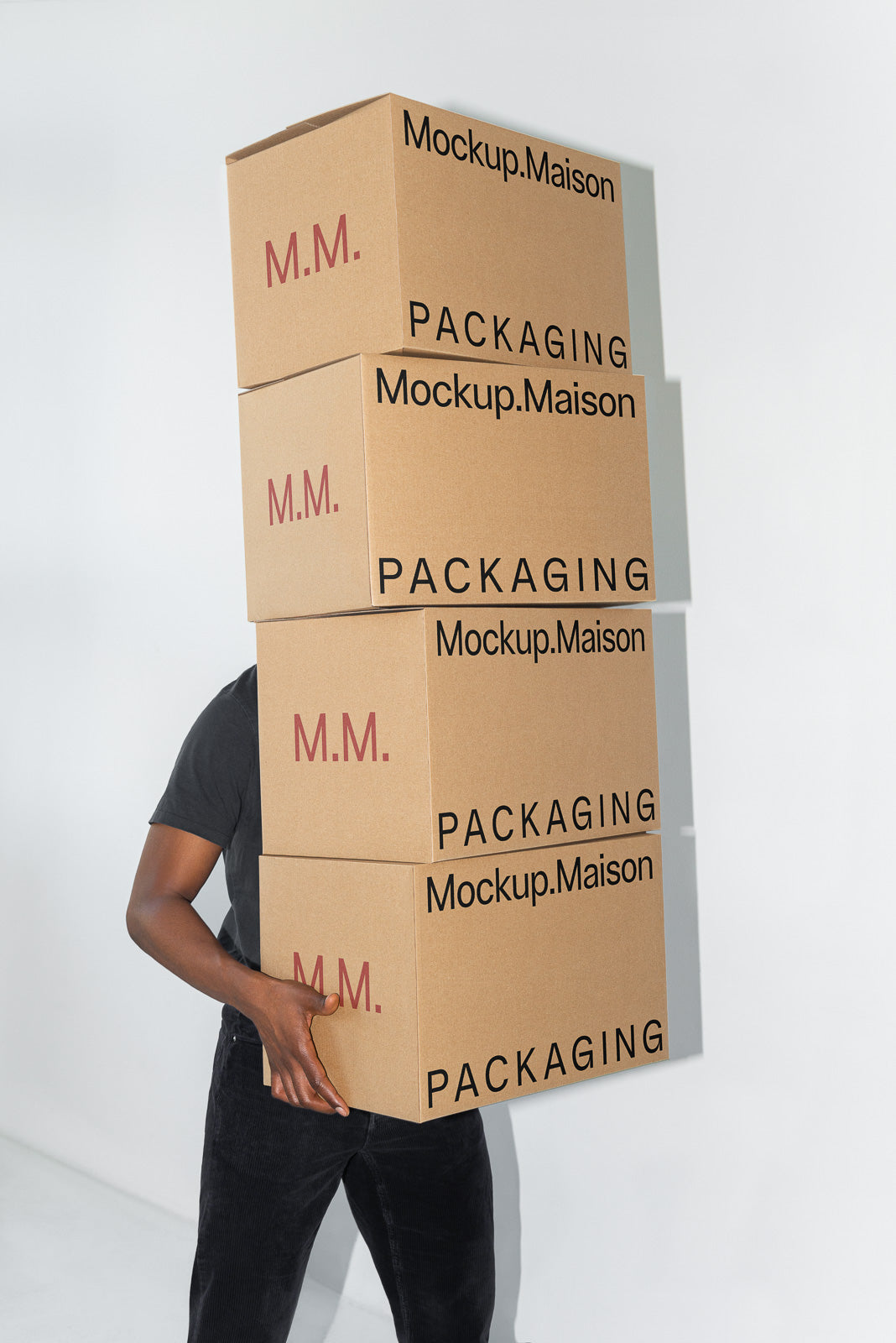 PSD mockup of a person carrying three stacked cardboard boxes labeled "Mockup.Maison" with "PACKAGING" text, partially obscuring their face.