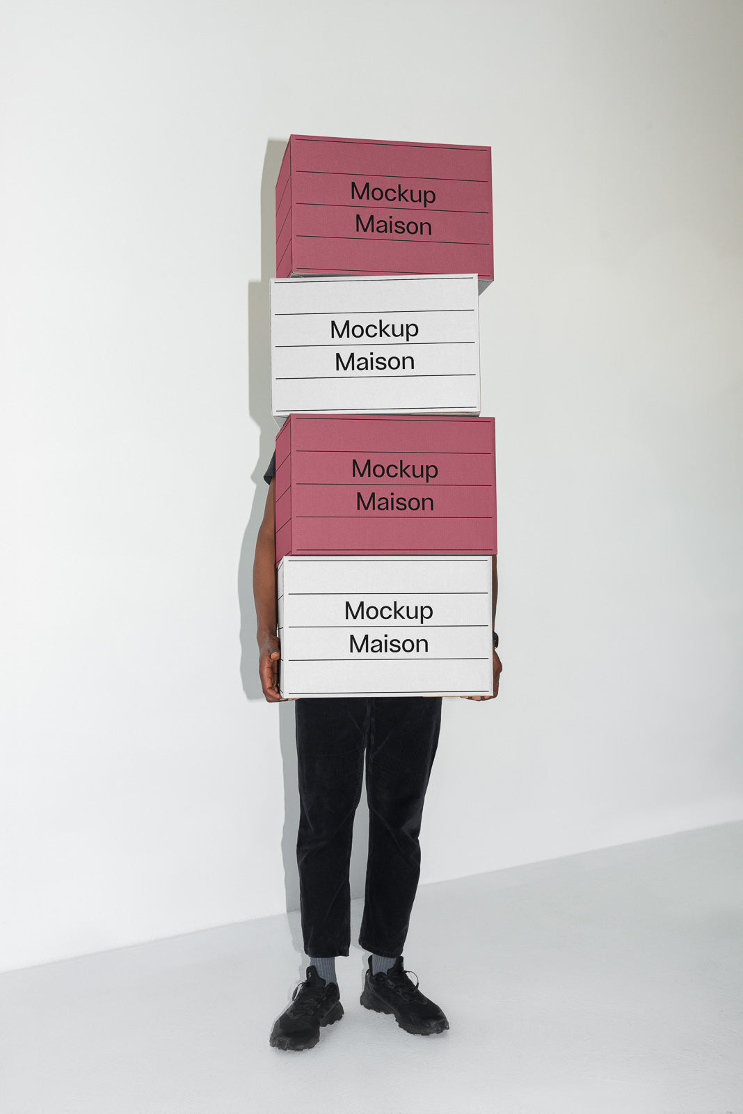 PSD mockup of a person holding a tall stack of boxes labeled "Mockup Maison," partially obscured by the packages, against a plain background.