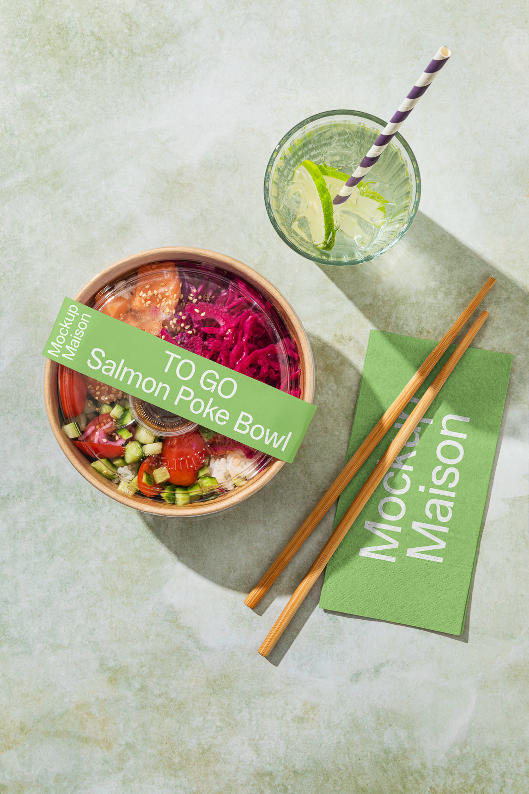PSD mockup of a salmon poke bowl with vibrant vegetables, accompanied by chopsticks, a green napkin, and a citrus drink with a straw on a textured surface.