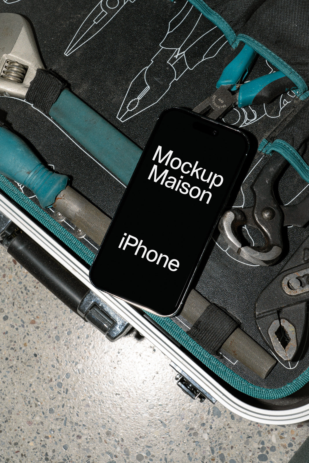 PSD mockup of a smartphone placed among tools in a toolbox, featuring text on the screen reading "Mockup Maison iPhone."