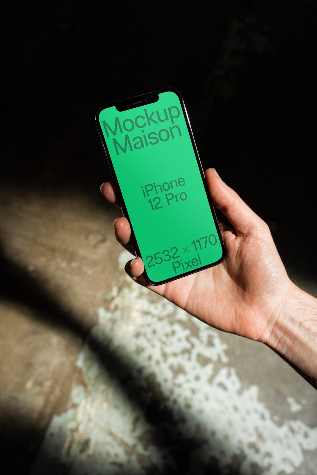 PSD mockup of a hand holding an iPhone 12 Pro with a green screen displaying text: "Mockup Maison, iPhone 12 Pro, 2532 x 1170 Pixel".
