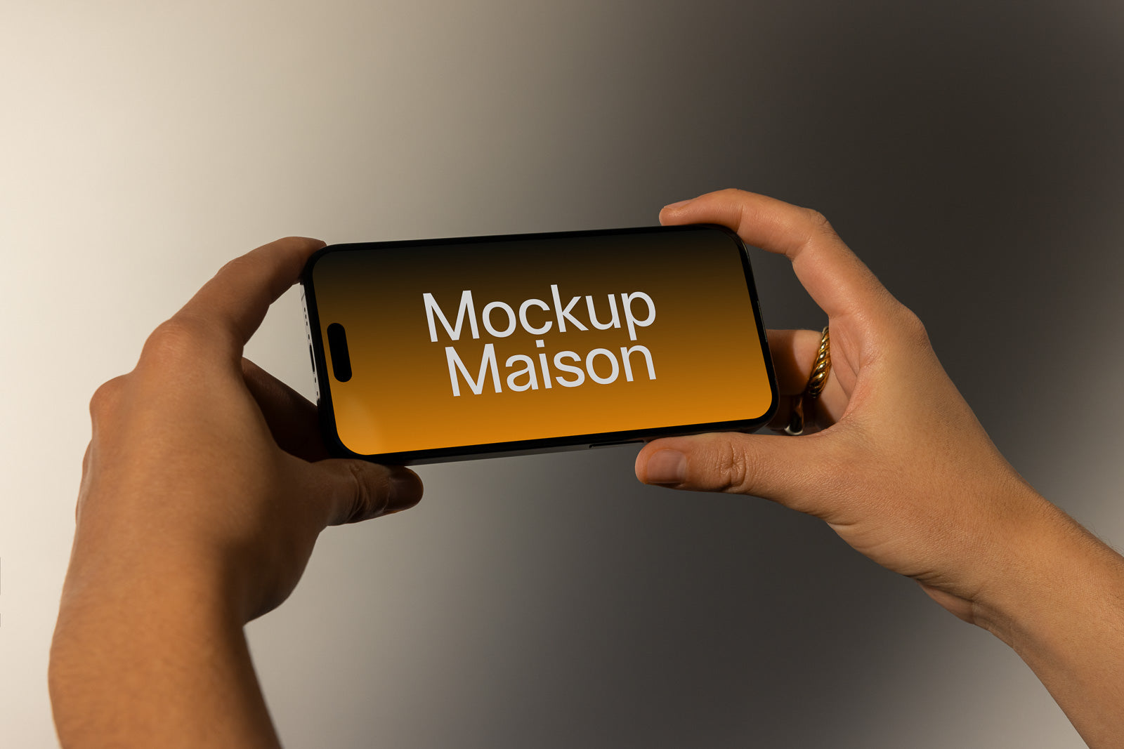 PSD mockup of hands holding a smartphone horizontally displaying "Mockup Maison" on an orange gradient screen.