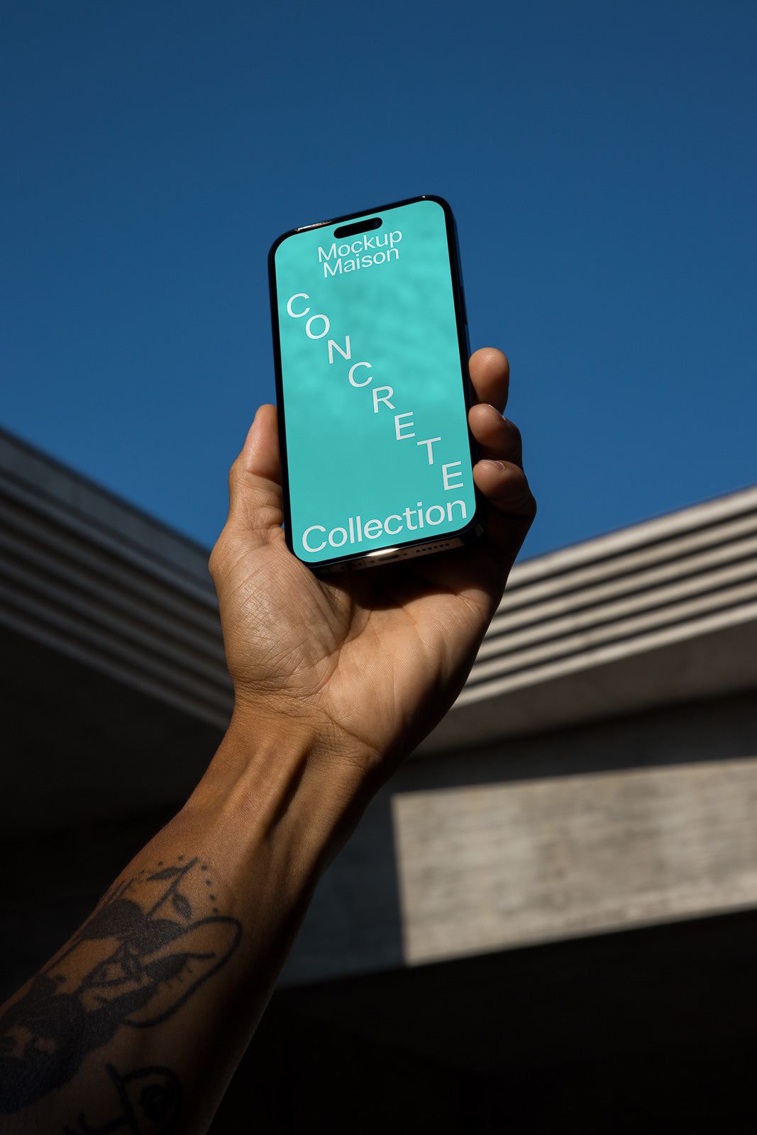 PSD mockup of a smartphone held in hand, displaying a "Concrete Collection" design with a blue-green background against a clear blue sky.