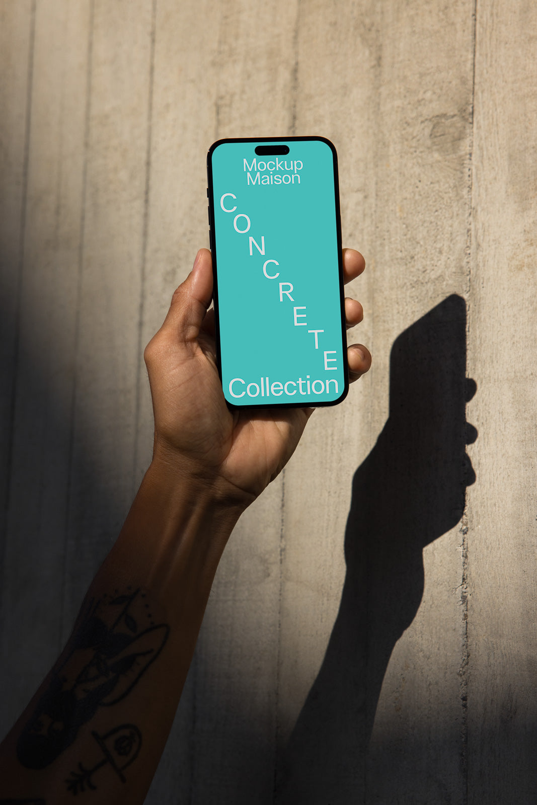 PSD mockup of a smartphone held in a hand against a concrete wall, displaying "Concrete Collection" on a teal screen with diagonal text arrangement.
