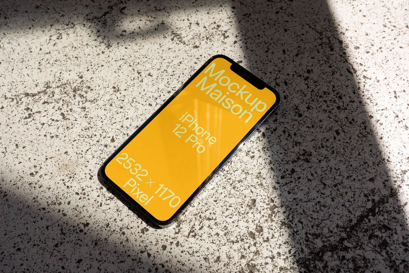 PSD mockup of an iPhone 12 Pro lying on a textured surface, displaying text "Mockup Maison" on a vibrant yellow screen with dimensions 2532 x 1170 pixels.