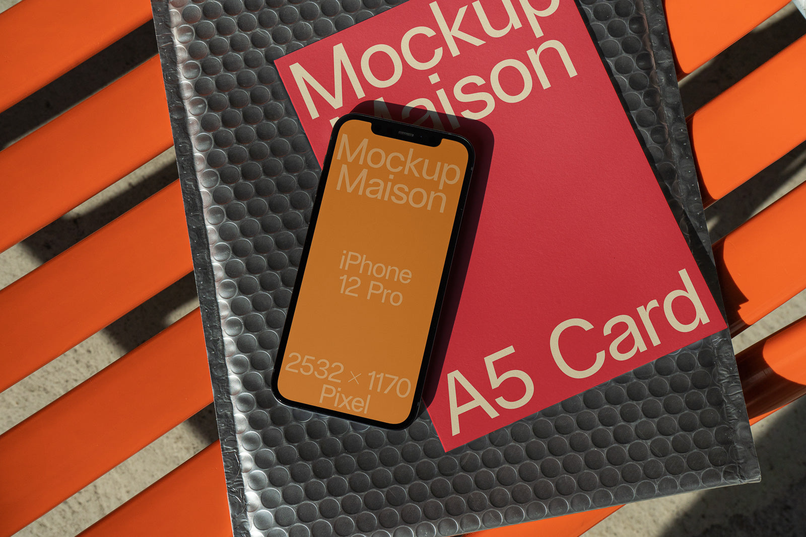 PSD mockup of an iPhone 12 Pro displaying text, resting on a textured surface and overlapping a red card labeled "A5 Card," on an orange slatted background.
