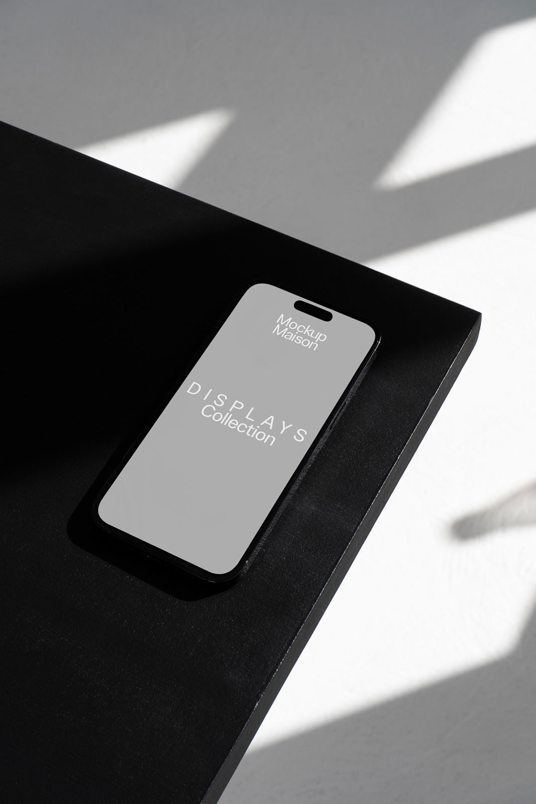 PSD mockup of a smartphone on a sleek black table, angled with shadows, displaying "Mockup Maison" and "DISPLAYS Collection" on the screen.