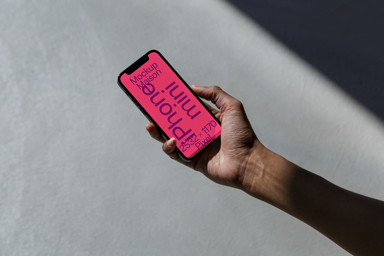 PSD mockup of a smartphone held in a hand, displaying bold text on a pink screen, set against a shadowed background.