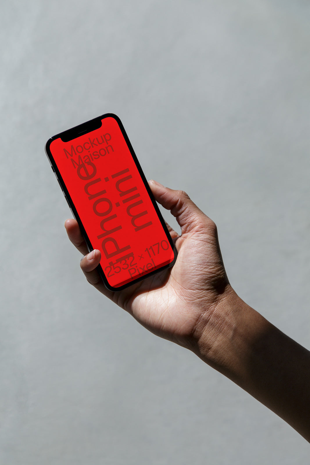 PSD mockup of a hand holding a smartphone with a red screen displaying text, showcasing dimensions and the term "mini" in bright lighting.