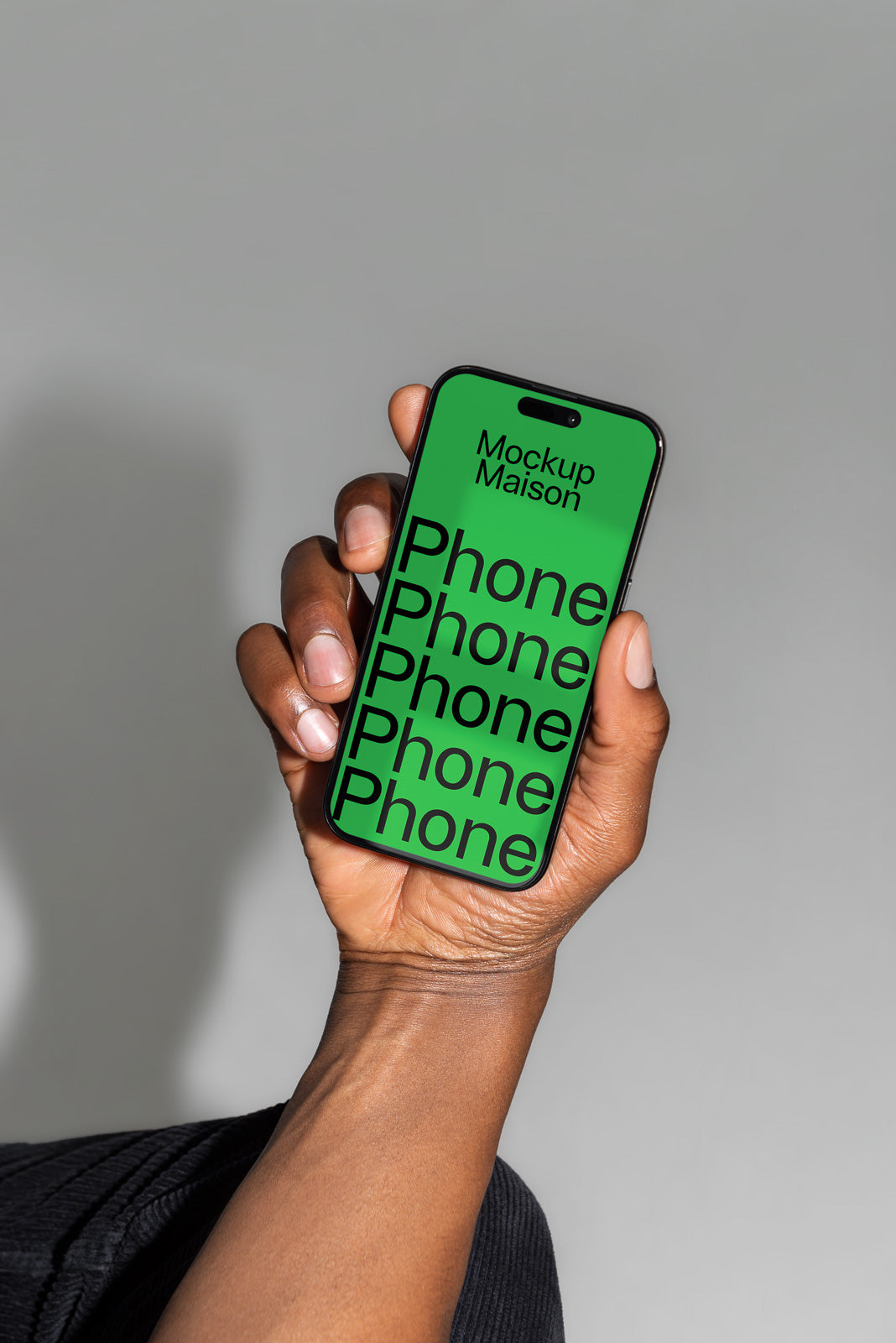 PSD mockup of a hand holding a smartphone with a green screen displaying "Mockup Maison" and the word "Phone" repeated in large black text.