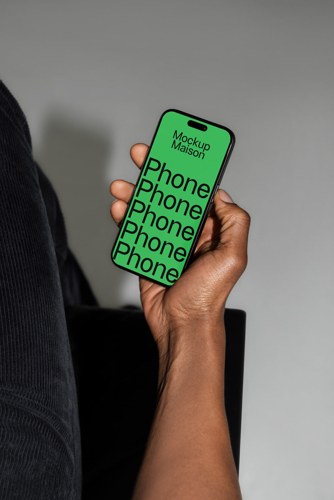 PSD mockup of a hand holding a smartphone displaying a green screen with repeated word "Phone" and "Mockup Maison" at the top.