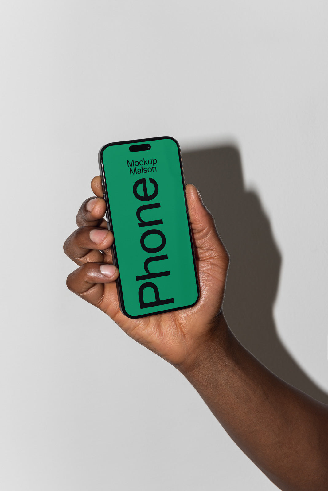 PSD mockup of a hand holding a smartphone with a green screen displaying "Mockup Maison" and "Phone," casting a shadow on a plain background.