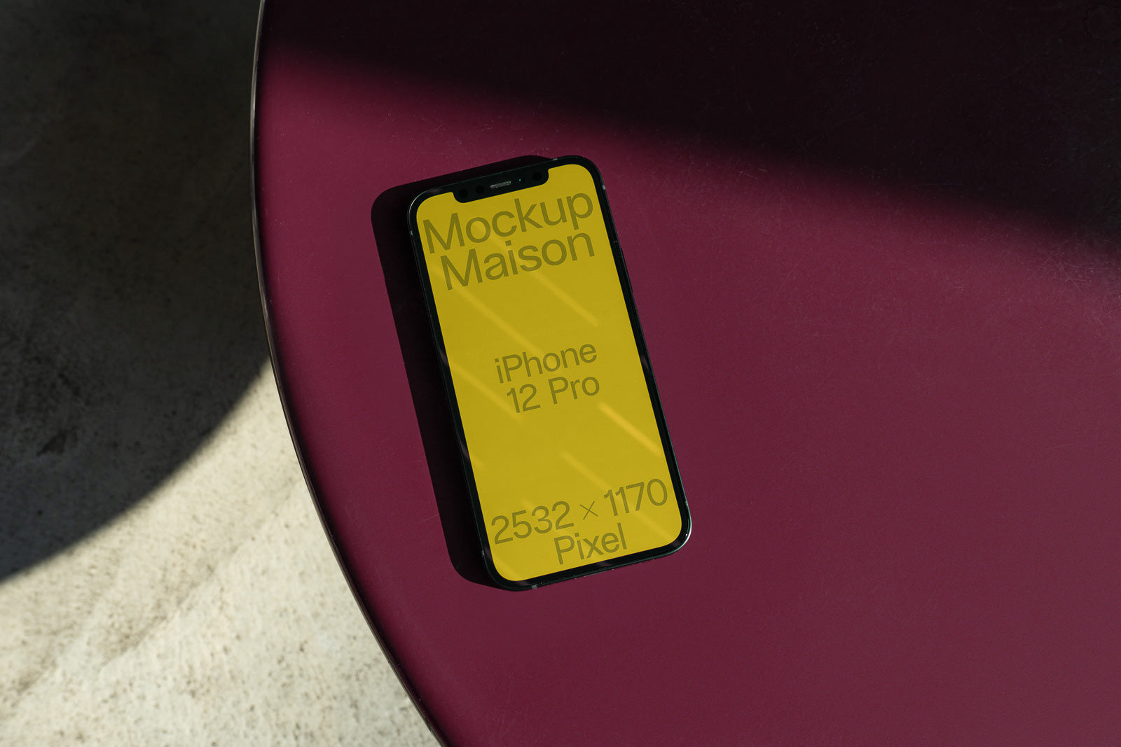 PSD mockup of an iPhone 12 Pro on a magenta table, screen displaying yellow background with "Mockup Maison" text and dimensions 2532 x 1170 pixels.