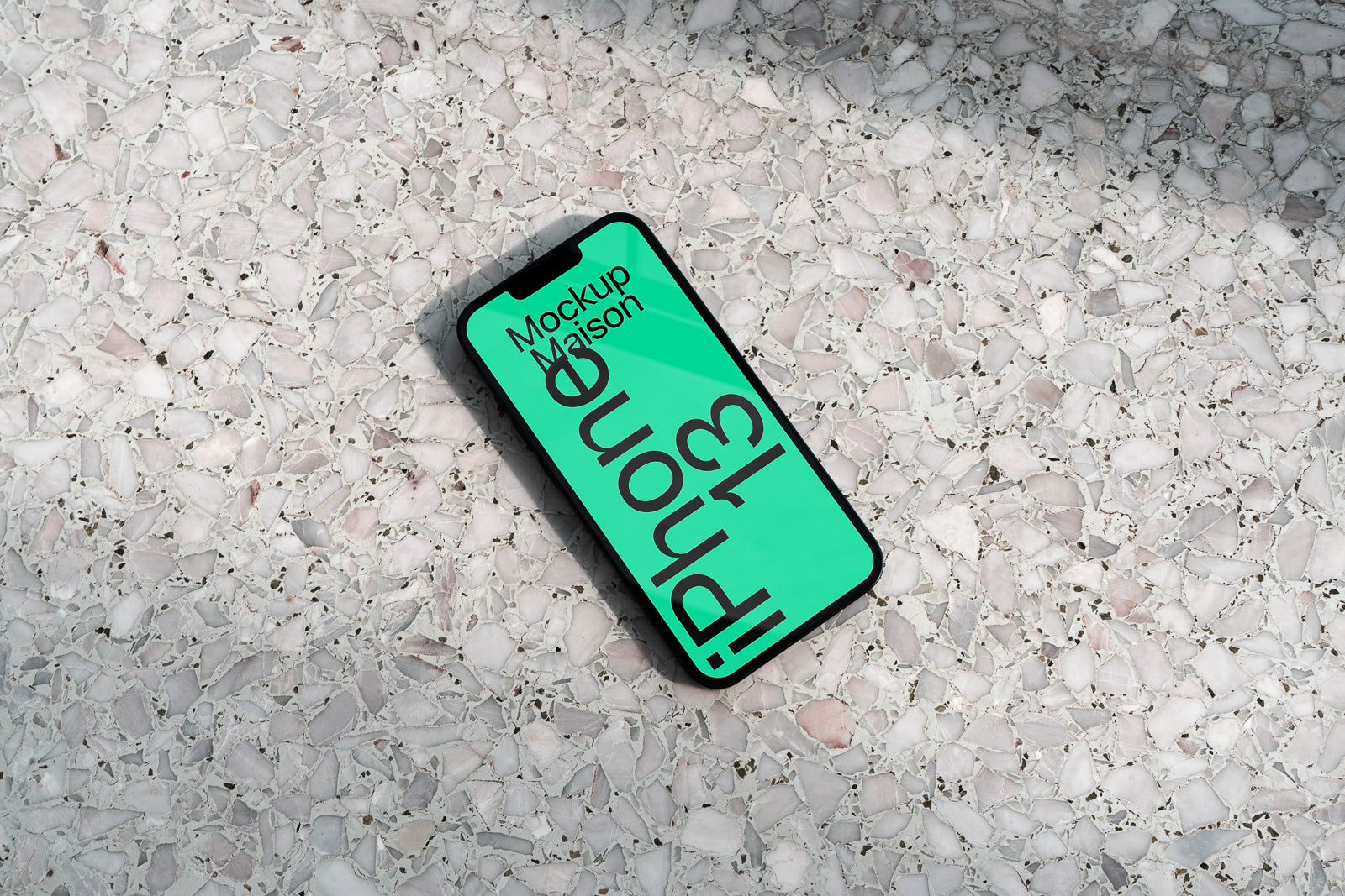 PSD mockup of an iPhone 13 on a light terrazzo surface, displaying a green screen with text.