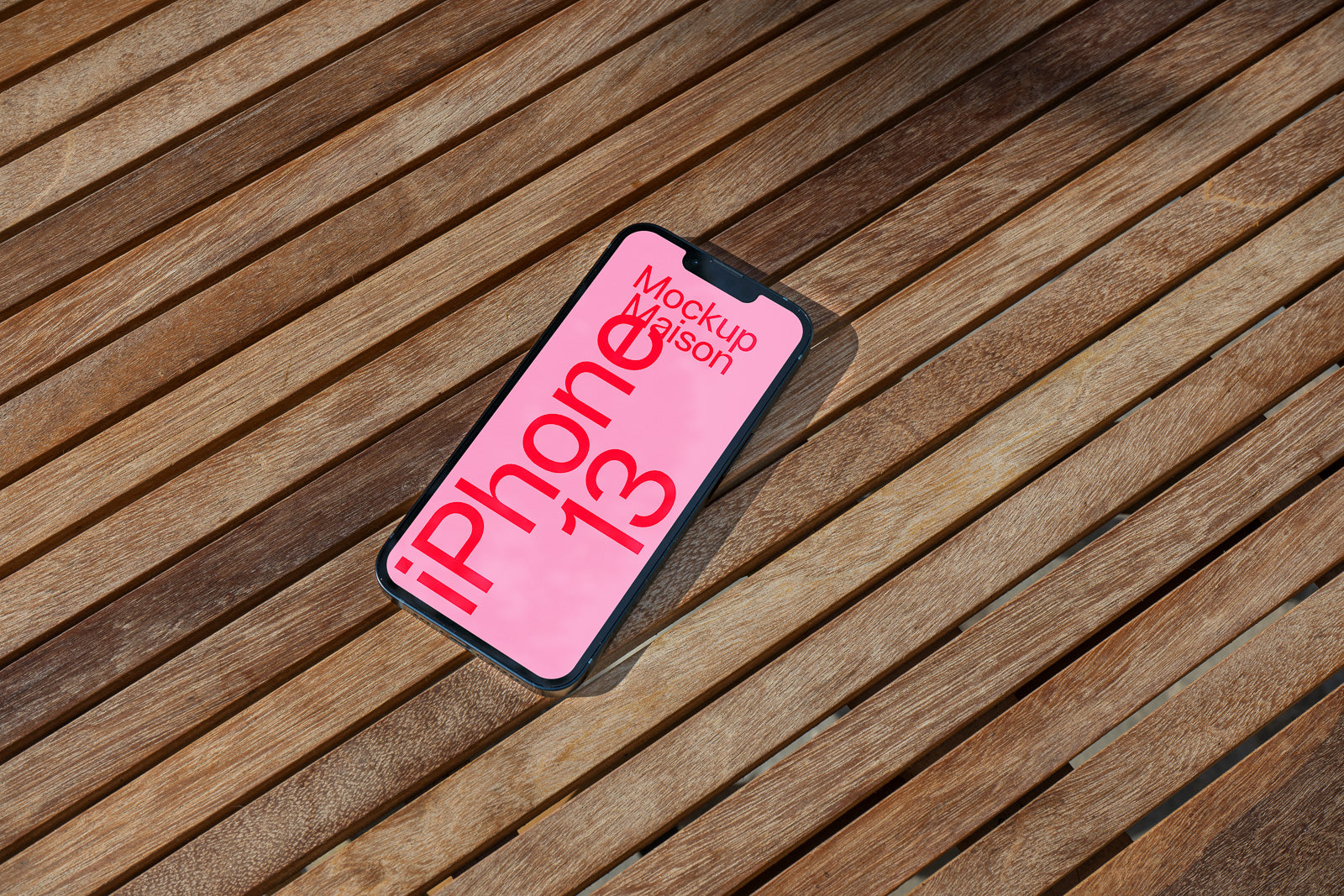 PSD mockup of a smartphone displaying bright pink screen with text, lying on a wooden surface, creating a realistic and natural setting.