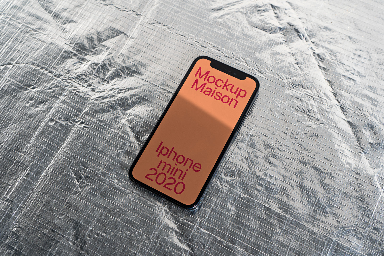 PSD mockup of an iPhone Mini 2020 displayed on a textured silver surface, with a colorful screen showing bold text.