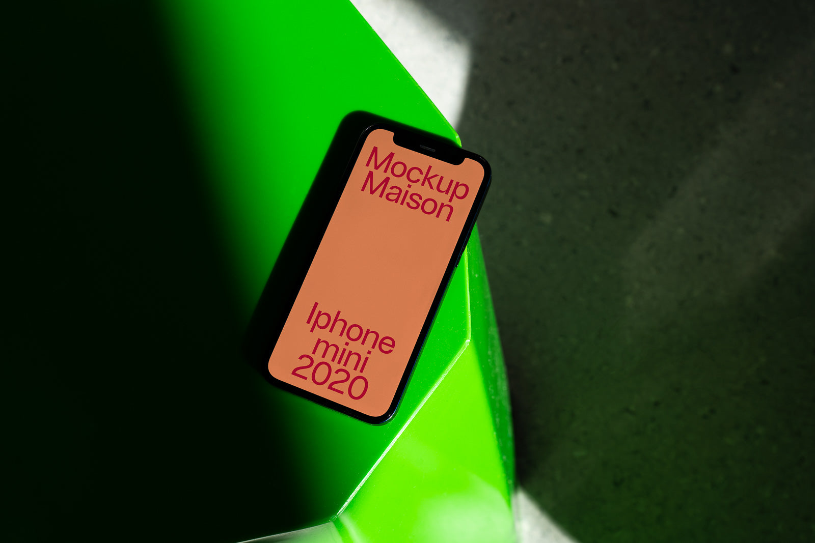 PSD mockup of iPhone Mini 2020 on a green surface, displaying "Mockup Maison" text on the screen.