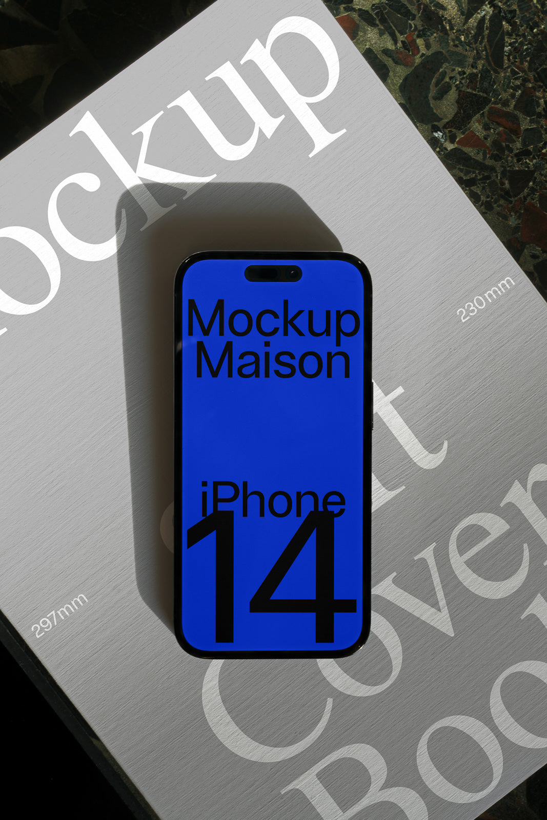 PSD mockup of an iPhone 14 placed on a partially visible book with bold typography, emphasizing the device's screen and sleek design.