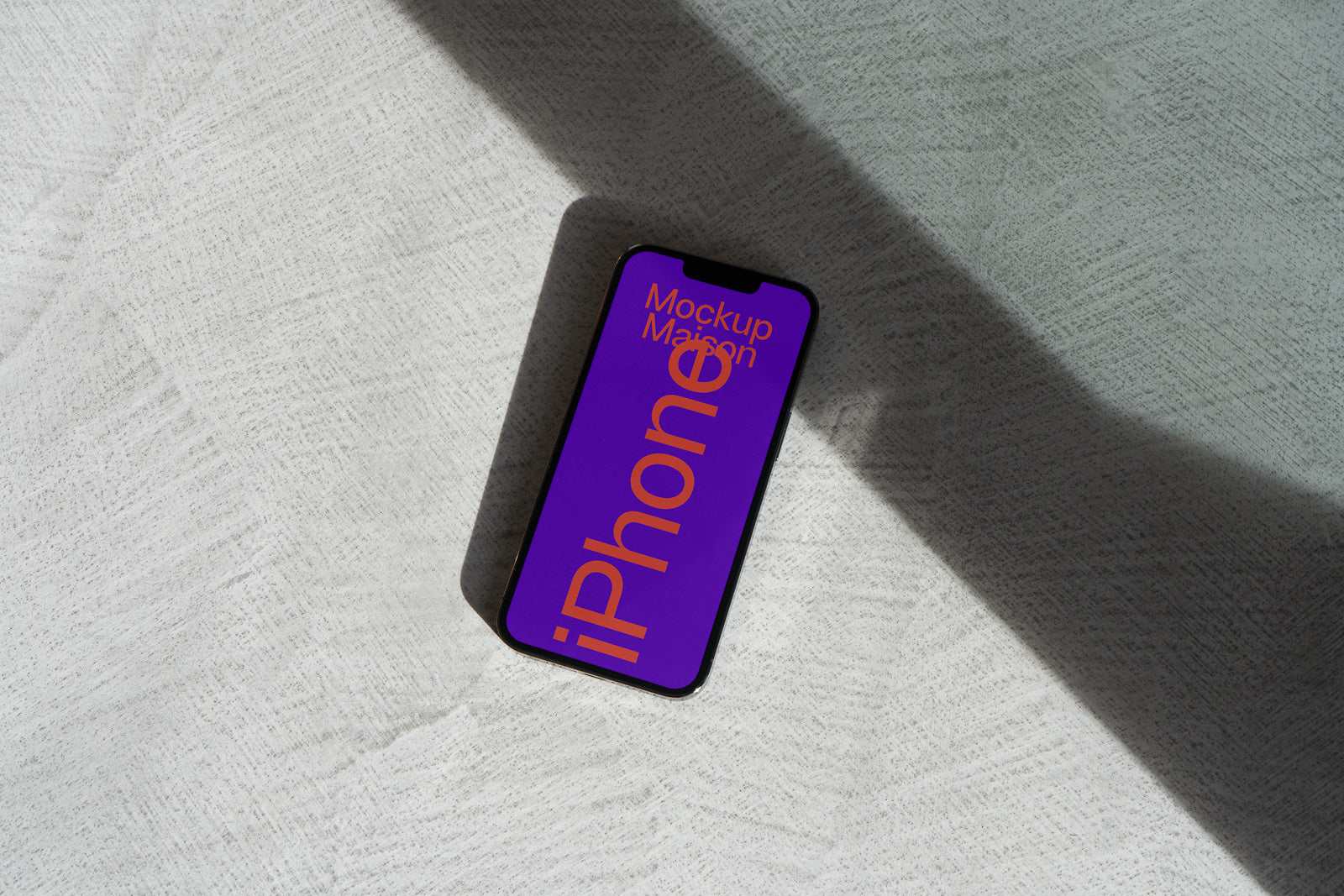 PSD mockup of a smartphone displaying "Mockup Maison" and "iPhone" in bold text on a purple screen, set against a textured surface with shadow play.