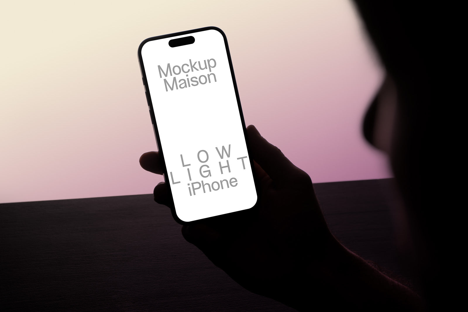 PSD mockup of a person holding an iPhone displaying text "Mockup Maison LOW LIGHT iPhone" against a gradient background.