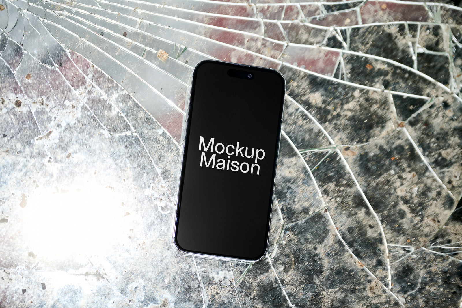 PSD mockup of a smartphone displaying 'Mockup Maison' on a dark screen, placed on a surface with a shattered pattern, providing a creative visual.