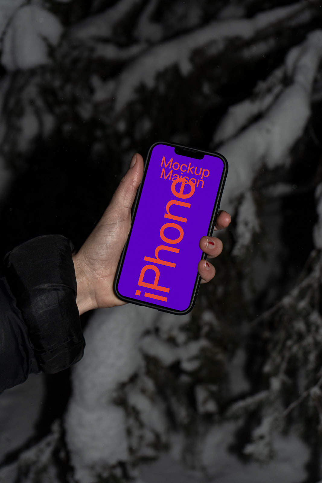 PSD mockup of a person holding a smartphone with a purple screen displaying "iPhone" text, set against a snowy, dark background.