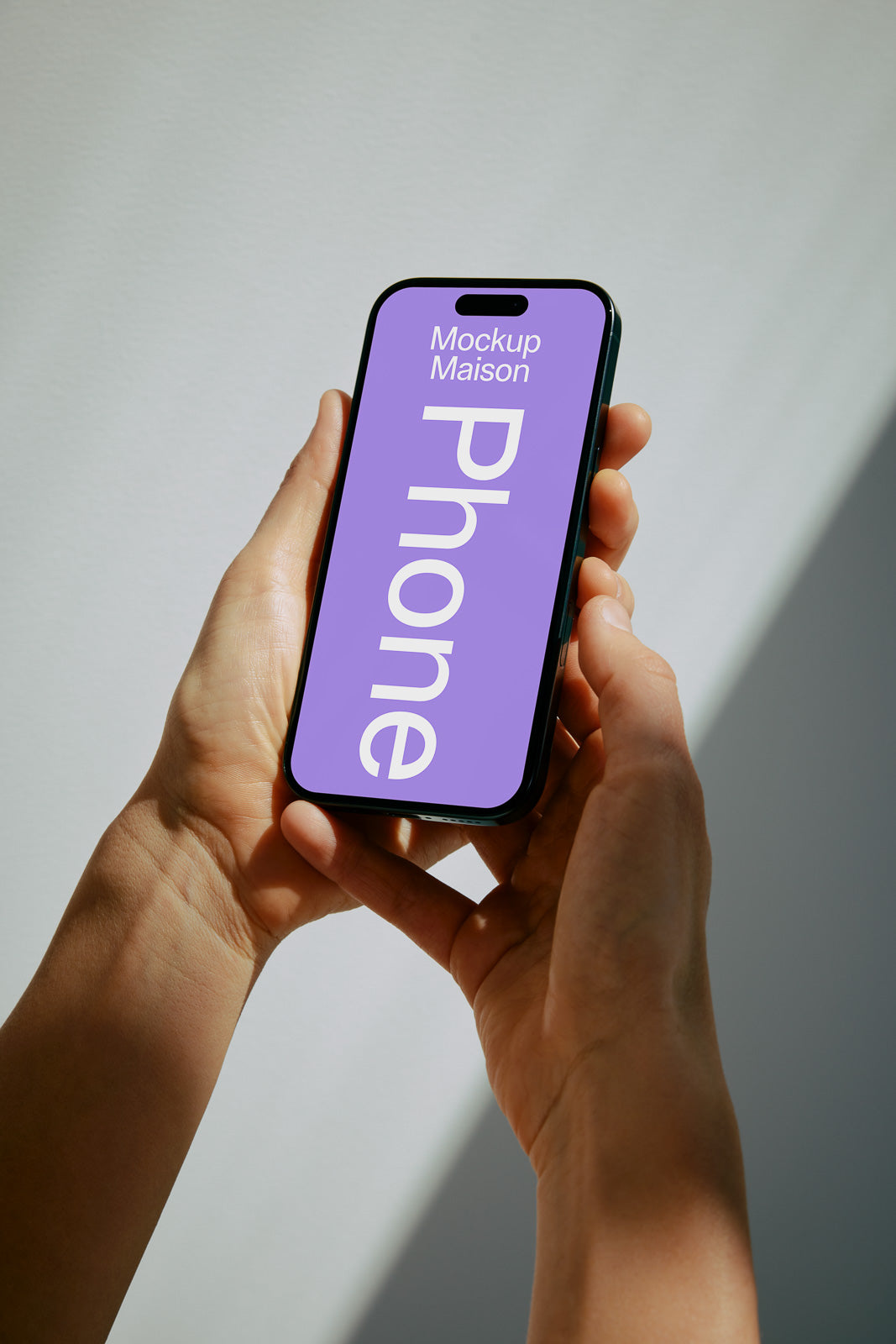 PSD mockup of a smartphone held in hands with a purple screen displaying "Mockup Maison Phone" text, against a light background, casting a soft shadow.