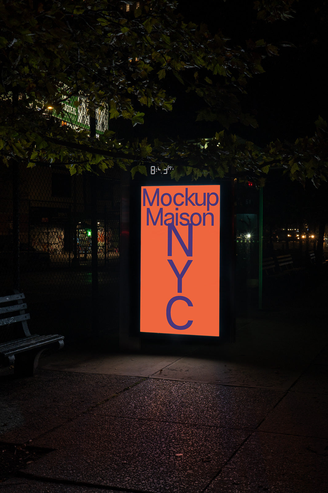 PSD mockup of an illuminated city bus stop advertisement at night, featuring bold text "Mockup Maison NYC" on an orange and blue background.