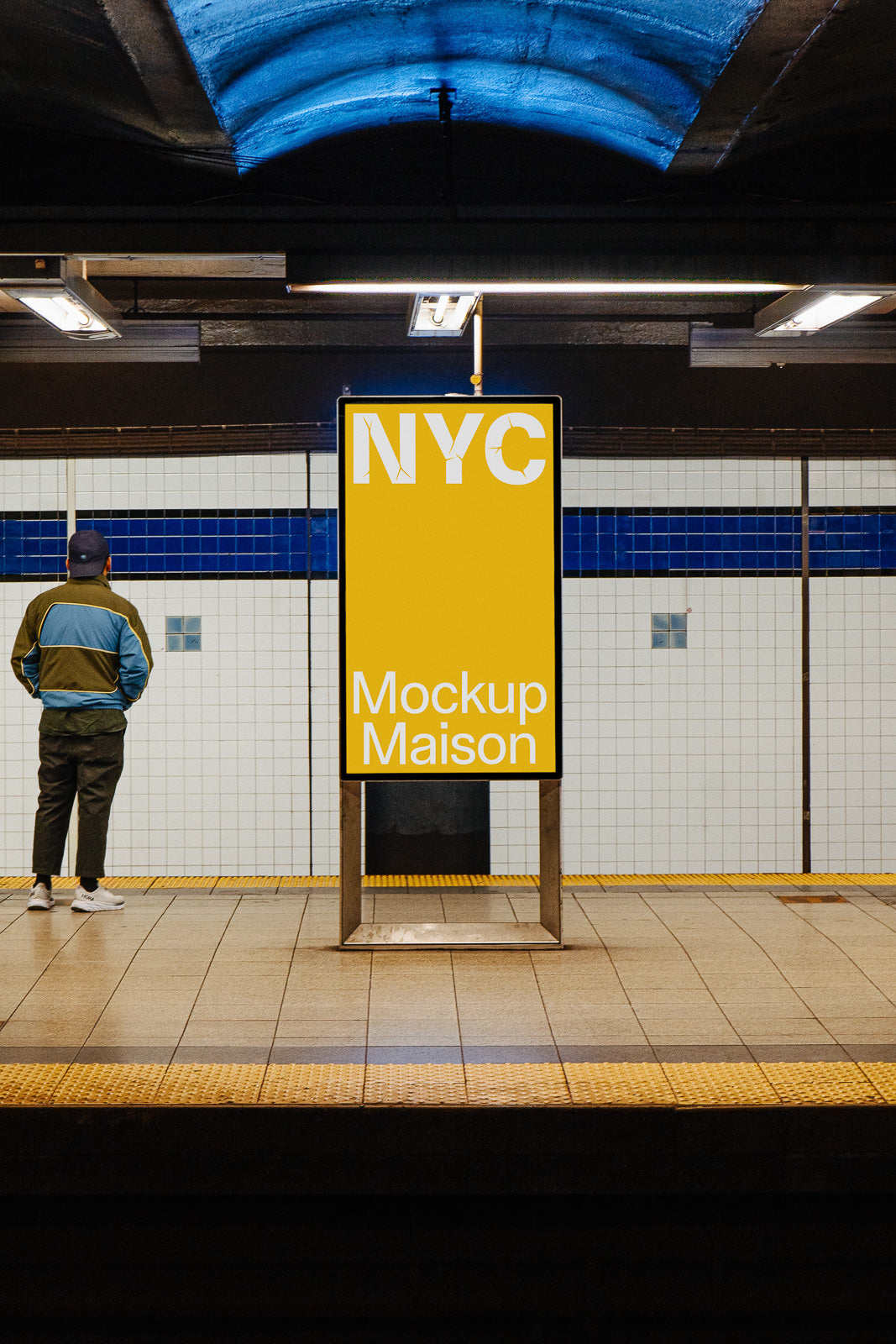 PSD mockup of an illuminated vertical billboard in a subway station with a person standing nearby, featuring the text "NYC Mockup Maison" on a yellow background.