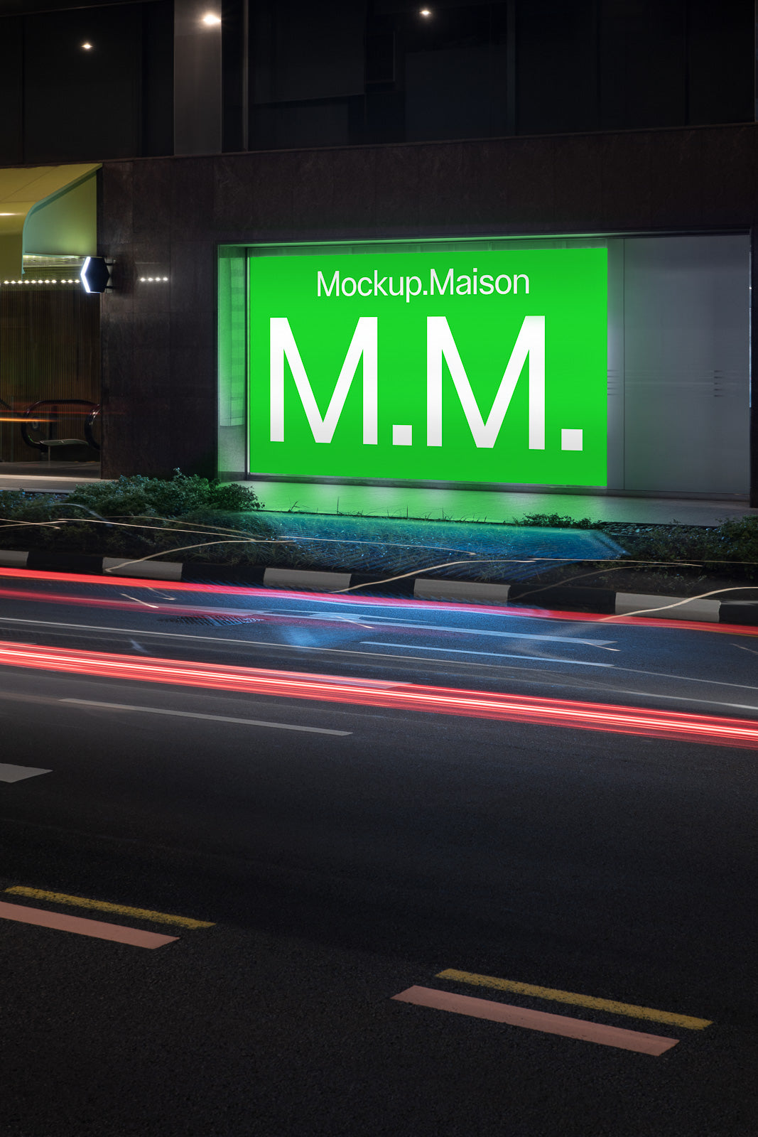 PSD mockup of an illuminated green billboard displaying "Mockup.Maison M.M." on a building facade at night with car light trails on the road.